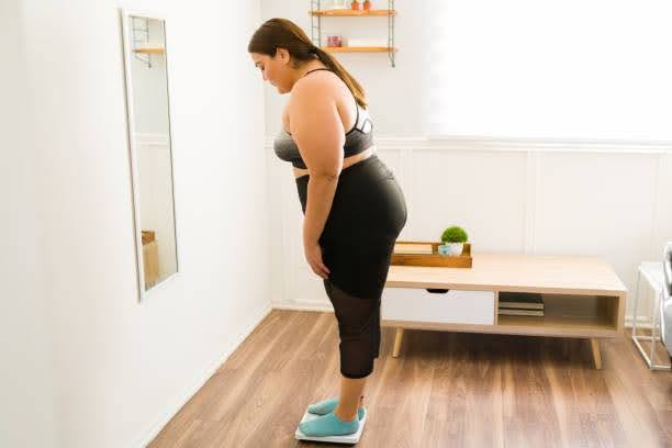 Woman checking her weight on a scale at home