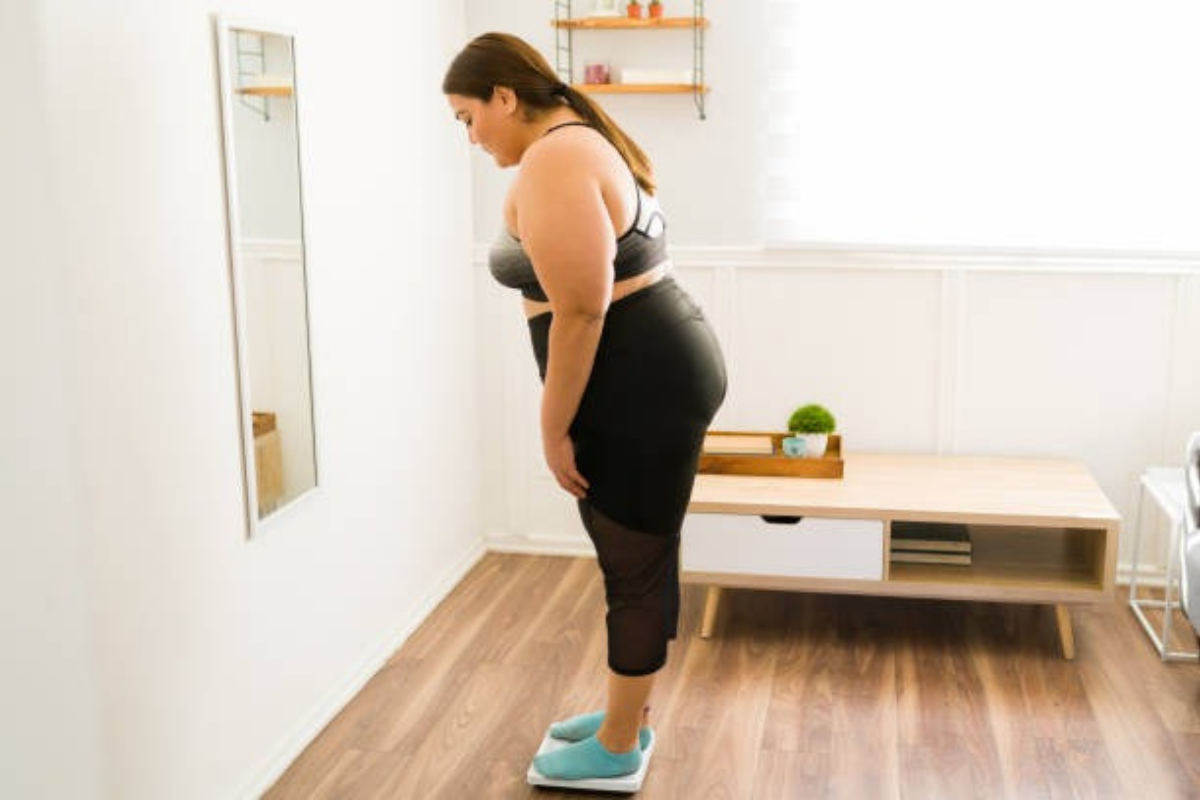 Woman checking her weight on a scale at home